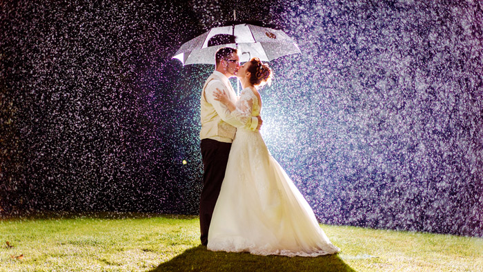 Hochzeitspaar im Regen unter einem Schirm